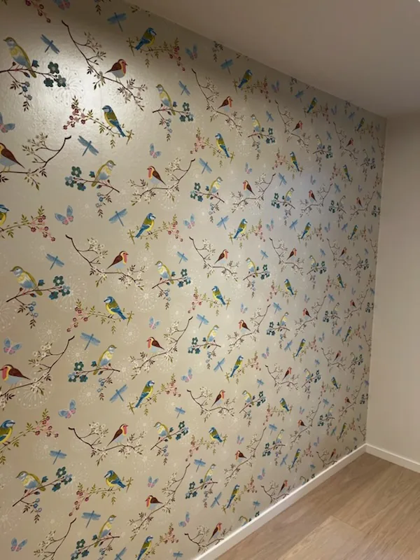 Tapet med fugler, øyenstikkere og blomstrende greiner på en hel vegg