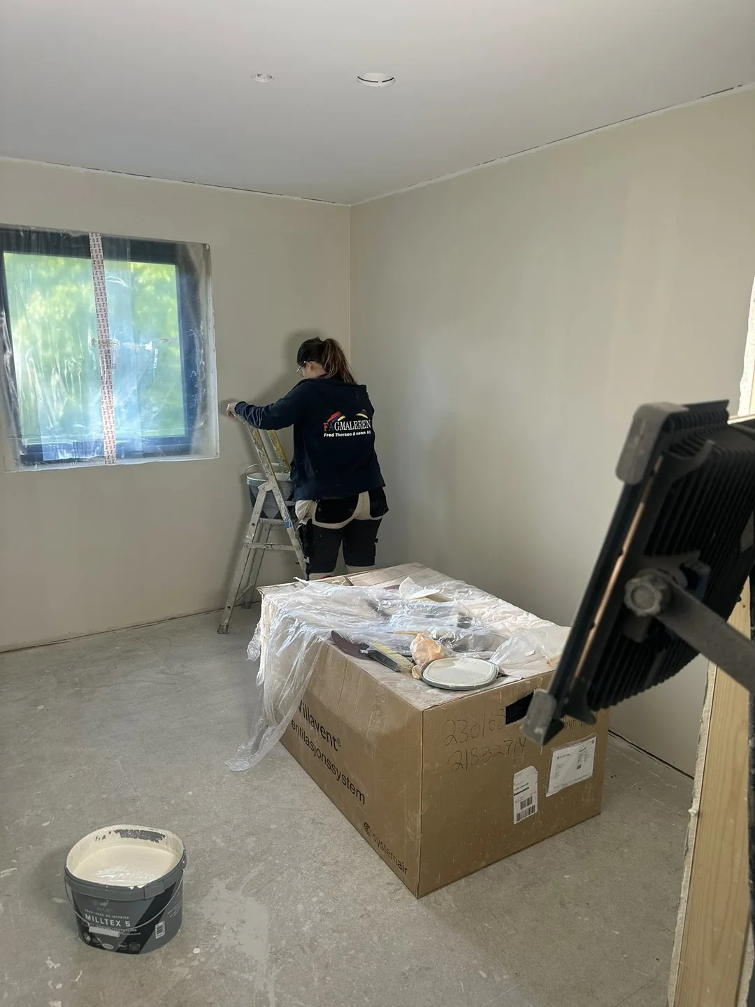 Maler fra Fagmaleren i arbeid ved et vindu i et rom under oppussing